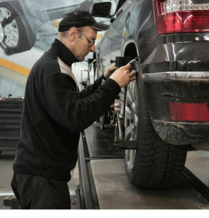 Mechanic working on a car tire in a car repair shop.